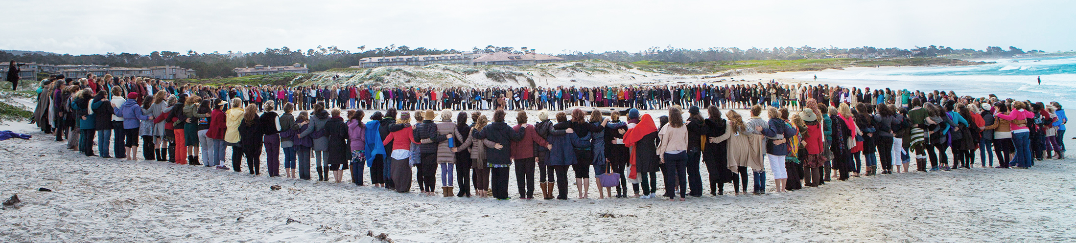 Participants holding hands in a circle on the beach